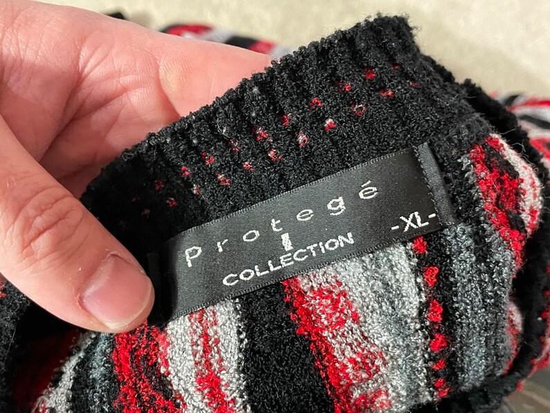 Peut inclure: Pull en maille ray&eacute; noir et rouge avec une &eacute;tiquette noire indiquant "Prot&eacute;g&eacute; Collection -XL-"