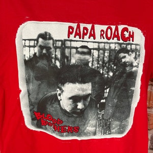 May include: Red t-shirt with a black and white image of a band, Papa Roach, with the text "Blood Brothers".