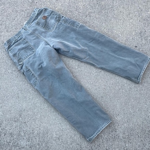 Puede incluir: Un par de pantalones de trabajo de mezclilla azul claro con un parche marr&oacute;n en el bolsillo trasero.