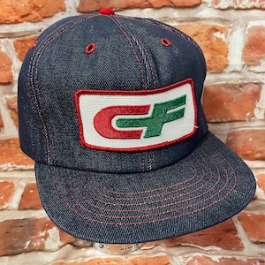 May include: A blue denim trucker hat with a red, white, and green embroidered patch that says "CF" on it.