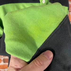 May include: Close-up of a black and green striped long-sleeve shirt with a button-up collar.