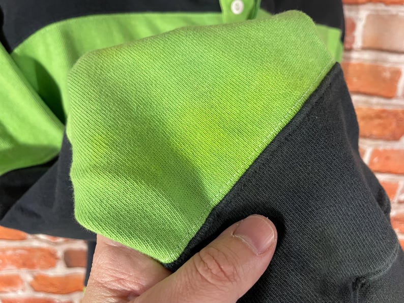 May include: Close-up of a black and green striped long-sleeve shirt with a button-up collar.