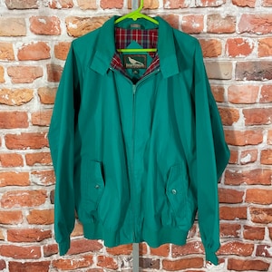 May include: A green jacket with a zipper closure and a plaid lining. The jacket has two pockets on the front and a brand label that reads "Field & Stream".