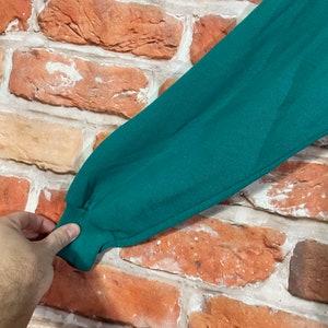 May include: Close-up of the dark green fabric sleeve of a sweatshirt. The fabric is soft and has a slight texture.