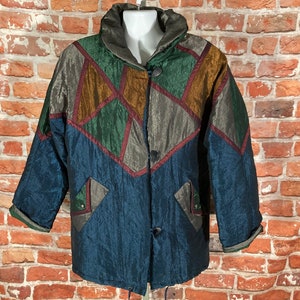 May include: A multi-colored jacket with a geometric pattern in shades of blue, green, brown, and gold. The jacket has a high collar and a zipper closure.
