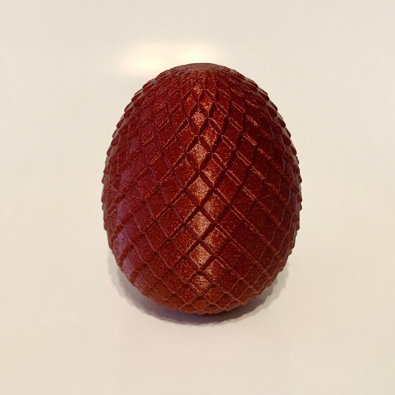 May include: A dark red dragon egg with a textured, diamond-shaped pattern.