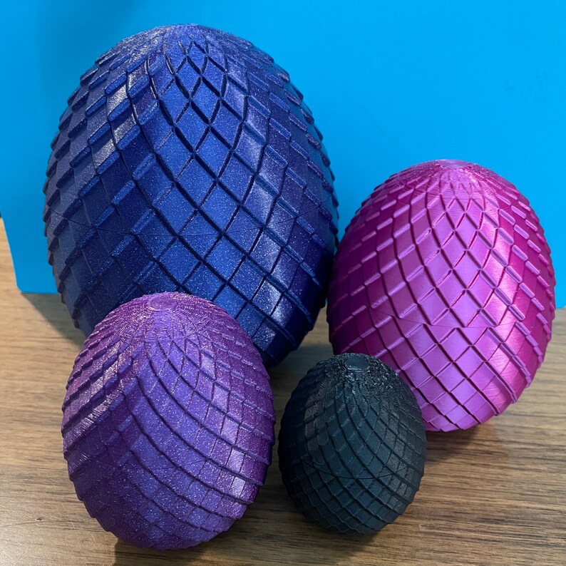 May include: Four decorative spheres with a geometric pattern. The largest sphere is dark blue, the next largest is pink, and the two smallest spheres are purple and black.