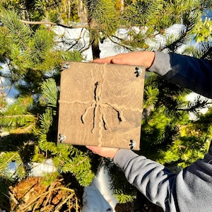 May include: A square wooden box with a rustic brown finish. The box is tied with twine and has metal corner accents.