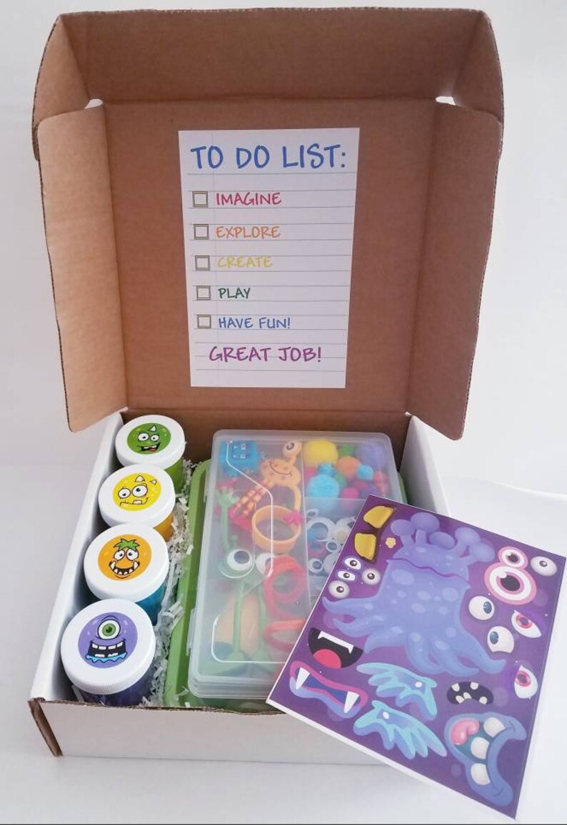 May include: A white cardboard box with a to-do list that says "Imagine, Explore, Create, Play, Have Fun! Great Job!" The box contains a set of monster-themed slime, googly eyes, pom-poms, pipe cleaners, and stickers.