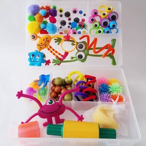 May include: A clear plastic storage box filled with colourful craft supplies for kids. The box contains googly eyes, pom poms, pipe cleaners, and other fun items.