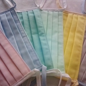 Può includere: Cinque maschere in tessuto di diversi colori: rosa, azzurro, verde chiaro, giallo e grigio. Le maschere sono plissettate e hanno lacci.