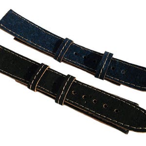 May include: Two watch straps made of cork, one blue and one black, with white stitching. The straps are shown against a white background.