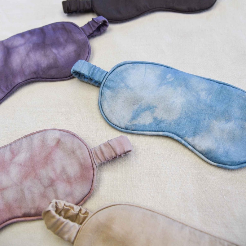 May include: Five different colored silk sleep masks with elastic straps. The masks are tie-dye patterned in shades of blue, purple, pink, and brown.