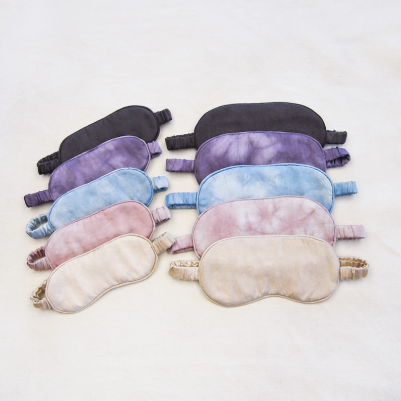 May include: A set of ten sleep masks in various shades of blue, purple, and pink. The masks are made of silk and have a tie-dye pattern.