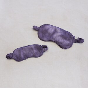 May include: Two purple sleep masks made of silk. The masks have a tie-dye pattern.