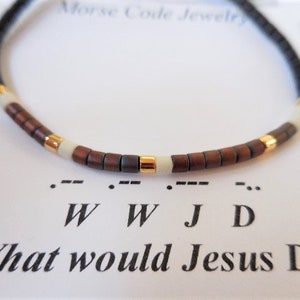 May include: A brown and black beaded bracelet with gold accents. The bracelet spells out "W W J D" in Morse code, which stands for "What Would Jesus Do?"