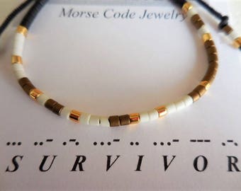 May include: A white and brown beaded bracelet with gold accents. The bracelet spells out the word "SURVIVOR" in Morse code.