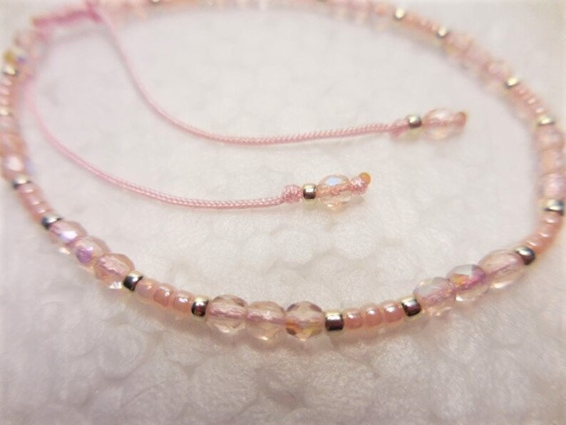 Puede incluir: Un brazalete de cuentas rosadas con cuentas plateadas y un cierre de cord&oacute;n rosa.
