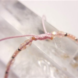 Puede incluir: Un brazalete de cuentas rosadas con cierre de cord&oacute;n rosa. Las cuentas son peque&ntilde;as y transl&uacute;cidas, con un ligero brillo.