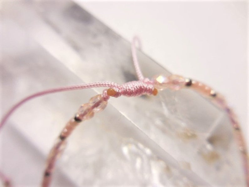 Puede incluir: Un brazalete de cuentas rosadas con cierre de cord&oacute;n rosa. Las cuentas son peque&ntilde;as y transl&uacute;cidas, con un ligero brillo.