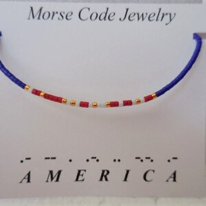 May include: A blue, white, and red beaded bracelet with gold accents spelling out "AMERICA" in Morse code.