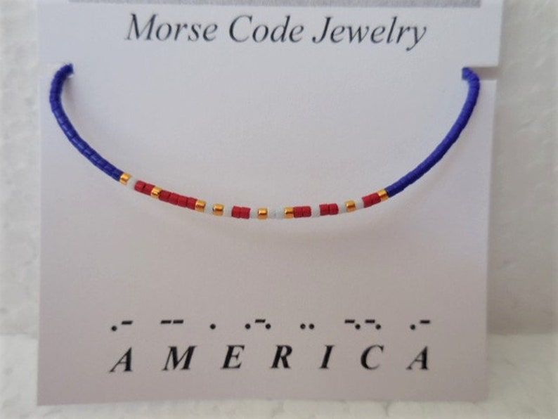 May include: A blue, white, and red beaded bracelet with gold accents spelling out "AMERICA" in Morse code.