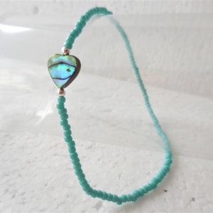 May include: A turquoise beaded anklet with a silver heart charm featuring an abalone shell inlay.