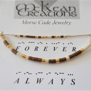 May include: A brown and white beaded bracelet with gold accents. The bracelet spells out "FOREVER" in Morse code. The card below the bracelet reads "Morse Code Jewelry" and shows the Morse code for "FOREVER" and "ALWAYS".