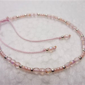 Puede incluir: Un delicado brazalete de cuentas rosa y plata con cierre de nudo deslizante. El brazalete est&aacute; hecho con peque&ntilde;as cuentas iridiscentes y cuentas espaciadoras plateadas.