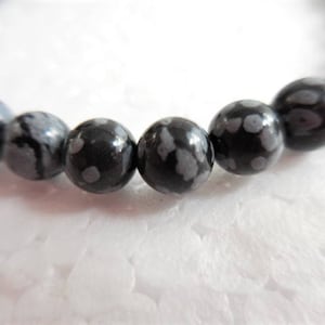 May include: A black and white speckled stone bracelet with round beads.
