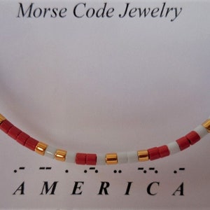 May include: A red, white, and blue beaded bracelet with gold accents. The bracelet spells out "AMERICA" in Morse code.