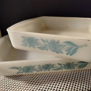 May include: Two white ceramic baking dishes with a blue floral design. The dishes are stacked on top of each other.