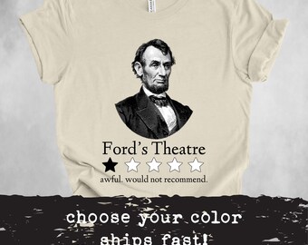 May include: A beige t-shirt with a black and white image of Abraham Lincoln. The text "Ford's Theatre" is below the image, followed by a one-star rating and the text "awful, would not recommend."