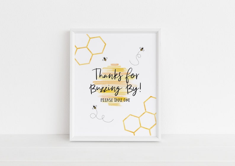 May include: White framed sign with a yellow and orange watercolor background. The sign says "Thanks for Buzzing By! Please take one." with a honeycomb pattern and bee illustrations.