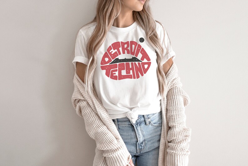May include: White t-shirt with a red lip design that says "Detroit Techno" in black text.