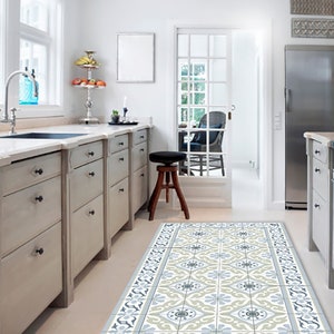 May include: A kitchen with light gray cabinets, a stainless steel refrigerator, and a patterned floor runner. The runner features a repeating floral design in shades of blue, gray, and cream. A window and door provide natural light.