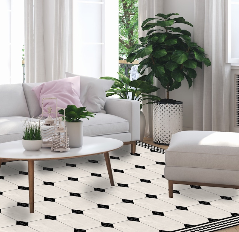 May include: A living room scene featuring a white sofa, a round coffee table, and a patterned floor. The floor has a cream background with black diamond-shaped accents. A large potted plant and a white ottoman are also visible.