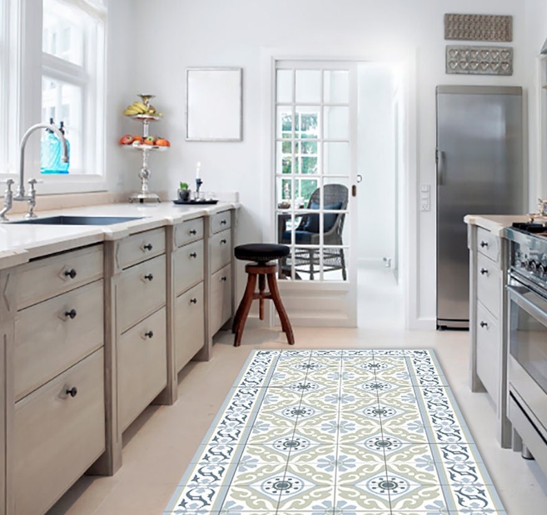 May include: A kitchen with light gray cabinets, a stainless steel refrigerator, and a patterned floor runner. The runner features a repeating floral design in shades of blue, gray, and cream. A window and door provide natural light.