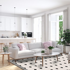 May include: A bright, modern living space with white walls, cabinetry, and furniture. A white sofa with pink pillows sits on a black and white patterned rug. The room features large windows with white curtains, and a kitchen island with bar stools.