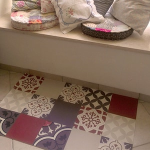 May include: A patterned floor mat with a patchwork design featuring various geometric shapes and floral motifs in shades of red, white, grey, and brown.