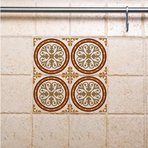 Op de afbeelding: Vier decoratieve tegel stickers met een geometrisch patroon in bruin, goud en wit. De stickers zijn in een vierkant patroon gerangschikt.