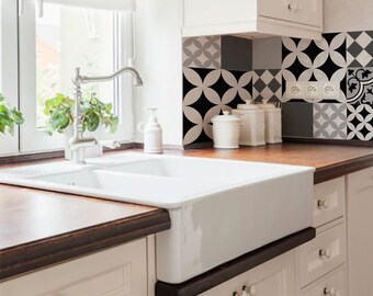 May include: A white porcelain farmhouse sink with two basins sits on a dark brown countertop in a kitchen. The backsplash is a black and white geometric tile pattern.