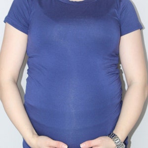 Puede incluir: Una mujer con una camiseta azul lisa de manga corta y ajustada.