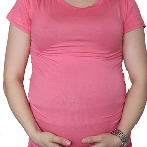 Puede incluir: Una camiseta de maternidad rosa de manga corta. La camiseta est&aacute; hecha de un tejido suave y el&aacute;stico y est&aacute; dise&ntilde;ada para ajustarse c&oacute;modamente sobre una barriga en crecimiento.