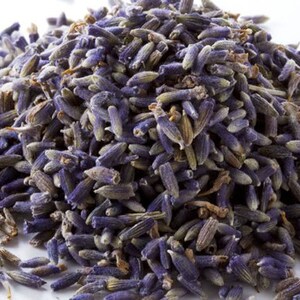 May include: A close-up of a pile of dried lavender buds. The buds are a deep purple color and have a slightly fuzzy texture.