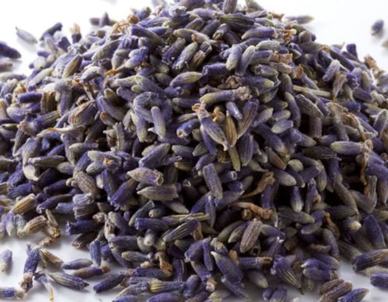 May include: A close-up of a pile of dried lavender buds. The buds are a deep purple color and have a slightly fuzzy texture.