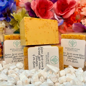 May include: Three bars of yellow soap with white labels. The labels read "Kojic Acid with Papaya and Turmeric Powder 4 oz Bar" and are from Bedlington Supplies.