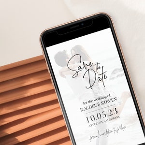 May include: A white save the date card with black text. The card features a photo of a couple embracing on a beach. The text reads "Save the Date" for the wedding of Rachel & Steven, 10.05.23, Anderson, California. Formal invitations to follow.
