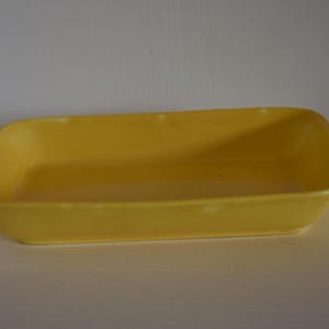 Puede incluir: Un plato para hornear rectangular de cerámica amarilla.