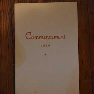 Op de afbeelding: Een witte kaart met de tekst "Commencement 1939" in rood gedrukt.